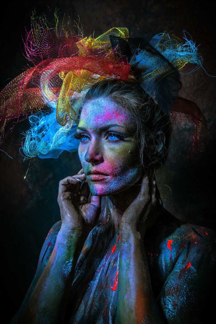 Three-quarter editorial portrait of Scarlet in vivid multicolor body paint and a sculptural headpiece